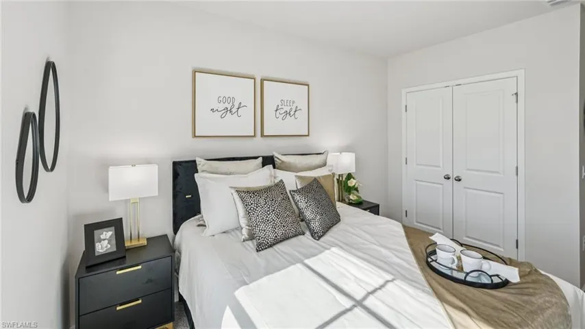 Bedroom with light-toned walls, a dark upholstered headboard, and dual panel closet doors