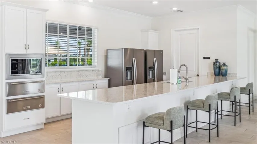 The kitchen features white cabinetry, stainless steel appliances, and light-colored countertops