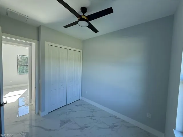 Unfurnished bedroom featuring marble finish flooring, a closet, and a ceiling fan