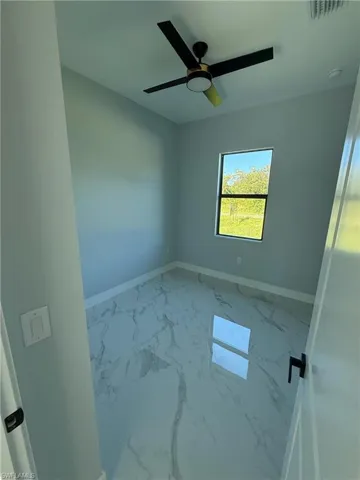 Unfurnished room with marble look tiles and baseboards