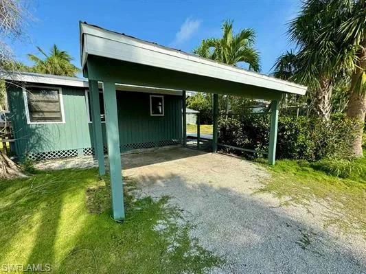 View of parking with driveway and a carport