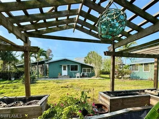 View of green lawn with a garden, a pergola, and a patio