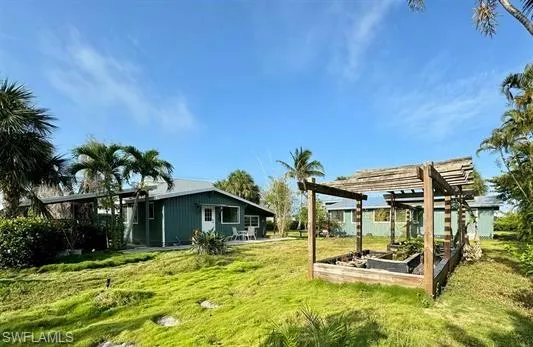 View of green lawn featuring a vegetable garden, a pergola, and a patio area