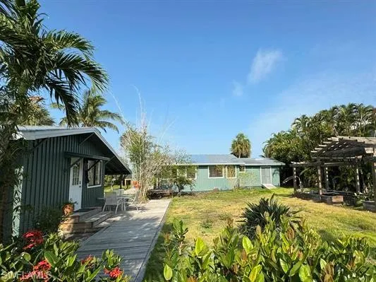 Rear view of property with a pergola, a wooden deck, a yard, and outdoor dining space