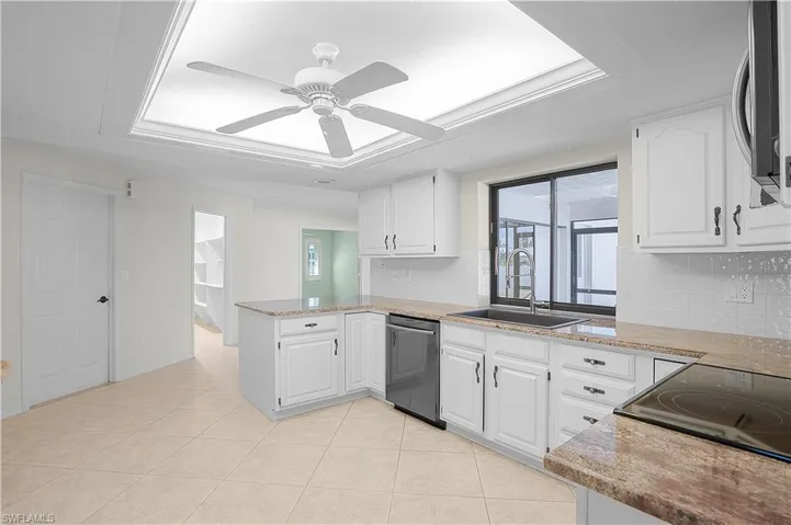 Kitchen featuring granite counters, white cabinetry, Samsung appliances, a black/grey sink, and a pass through window with exterior visibility to lanai/sun room