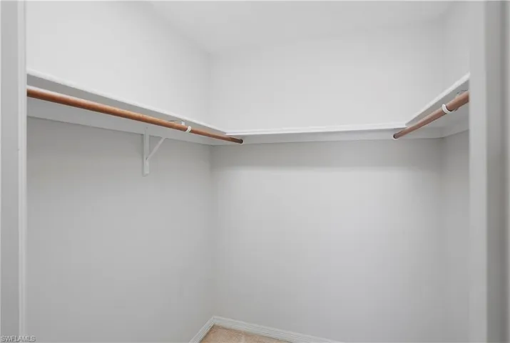 Walk-in closet with carpet flooring, white walls, and built-in shelving with hanging rods
