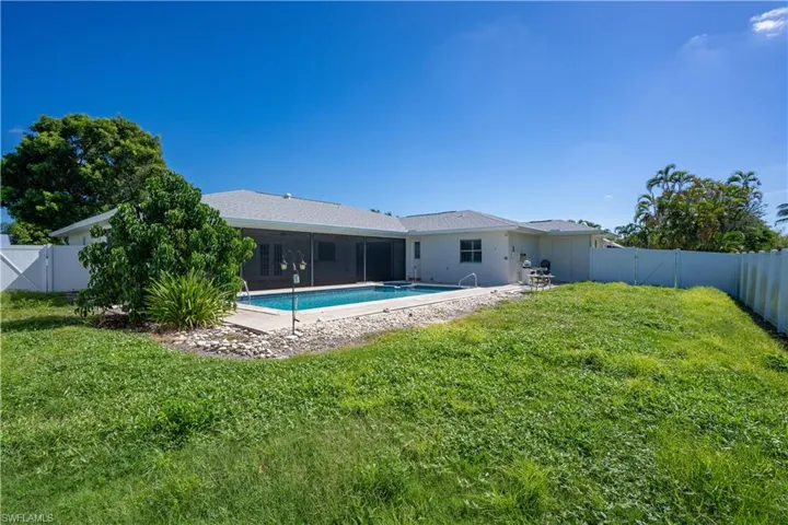 Expansive rear yard featuring a large pool, a screened lanai, and a white privacy fence- though you can't see it there's a shed for additional storage