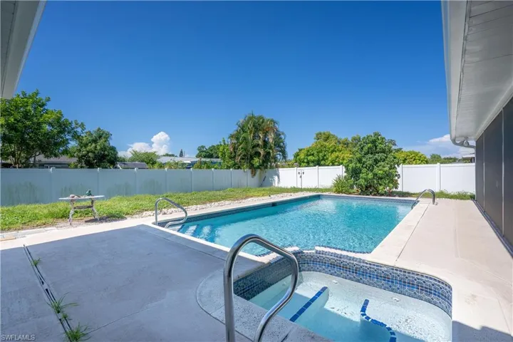 Rectangular swimming pool with integrated spa featuring mosaic tile accents, surrounded by a concrete patio. You can do laps in this pool. Includes a hot tub/spa.