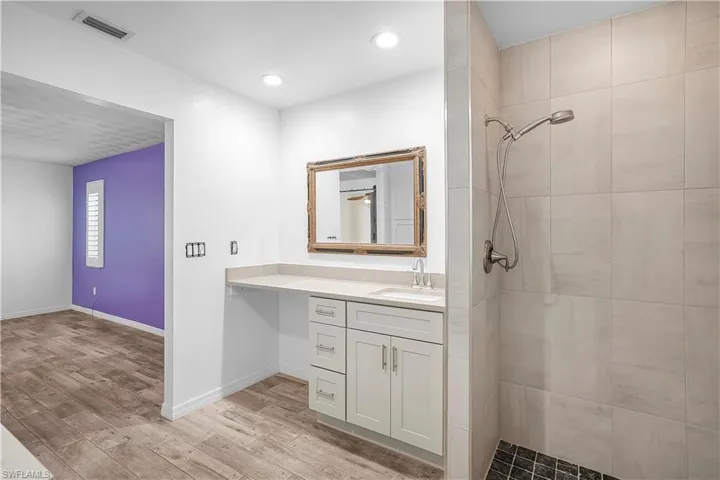 Walk-in shower with tiled walls and dark mosaic flooring, wide open for easy maneuvering