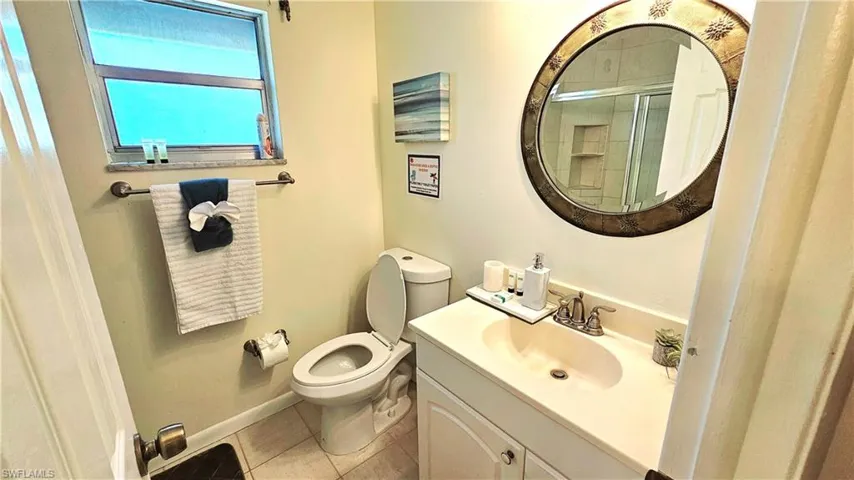 Bathroom with an enclosed shower, vanity, tile patterned floors, and toilet