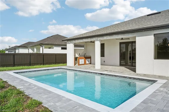 View of pool featuring a ceiling fan, a patio, and an outdoor kitchen