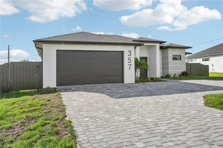 Prairie-style house featuring stucco siding, decorative driveway, and a garage