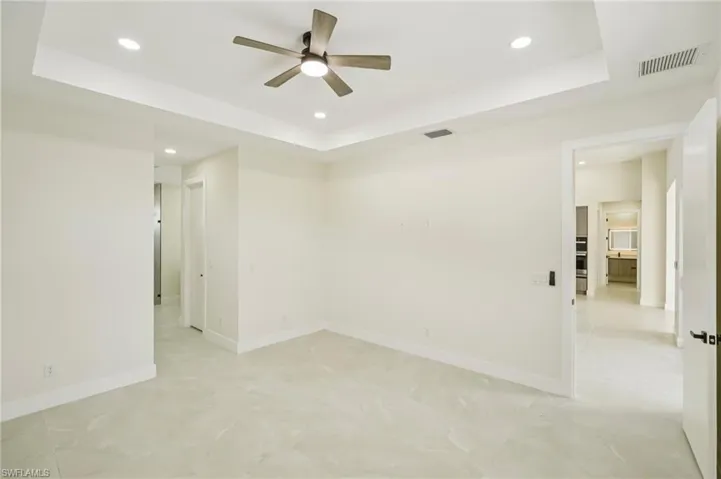 Empty room featuring a tray ceiling, recessed lighting, and a ceiling fan
