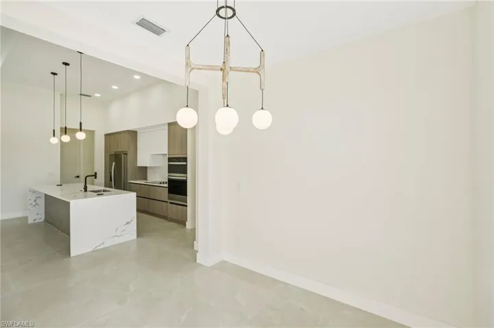 Kitchen with modern cabinets, decorative light fixtures, light stone countertops, recessed lighting, and stainless steel appliances