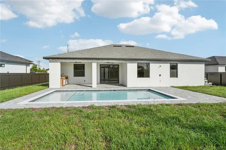 Back of property with a fenced backyard, a patio, stucco siding, and roof with shingles