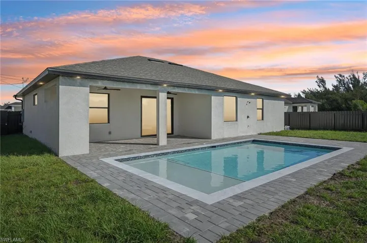 Back of property at dusk with a fenced backyard, a patio, and stucco siding