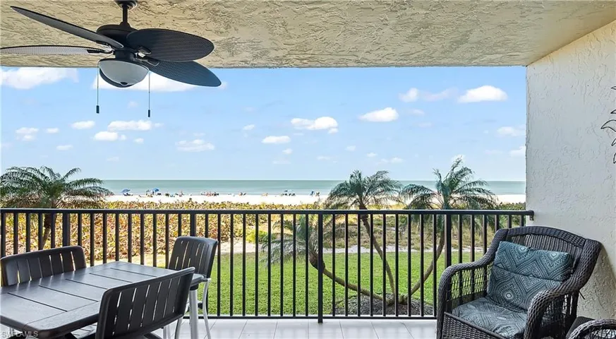 Balcony featuring a water view, a beach view, and ceiling fan