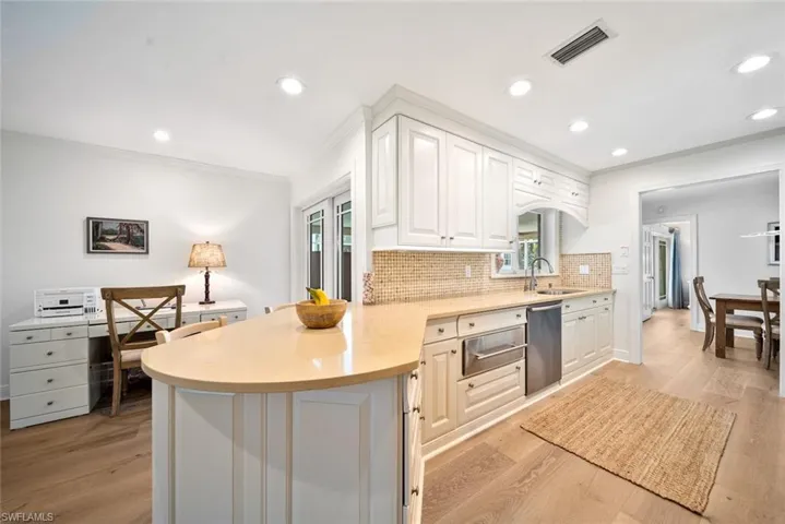 Kitchen with white cabinets, light hardwood / wood-style floors, plenty of natural light, and kitchen peninsula