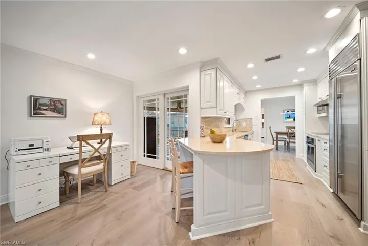 Kitchen with white cabinets, light wood-type flooring, stainless steel appliances, and tasteful backsplash