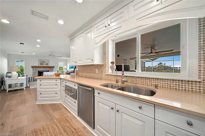 Kitchen featuring white cabinets, sink, dishwasher, and tasteful backsplash