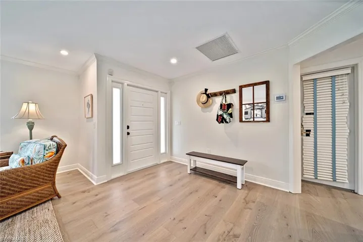 Entrance foyer with light hardwood / wood-style flooring and crown molding