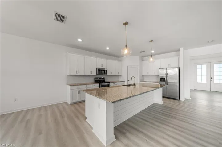 Kitchen featuring stainless steel appliances, light wood finished floors, white cabinetry, and recessed lighting