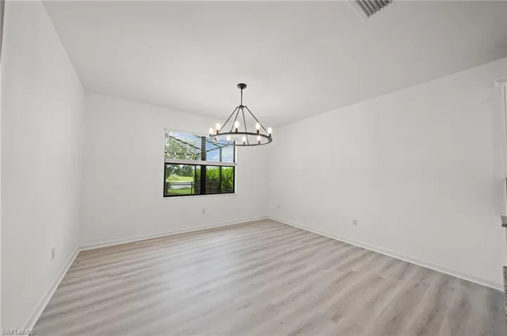Unfurnished room featuring light wood finished floors and a chandelier