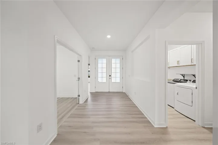 Corridor with washing machine and clothes dryer, light wood-type flooring, french doors, and recessed lighting