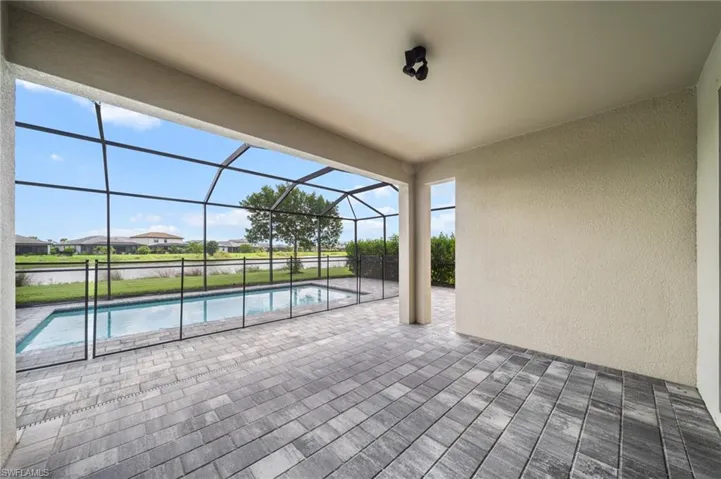 View of patio / terrace featuring an outdoor pool, glass enclosure, and a water view