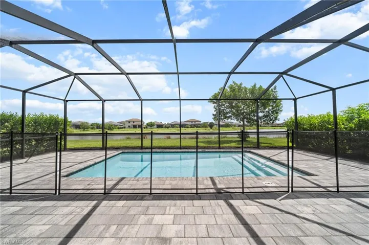 Outdoor pool with a patio, glass enclosure, and a water view