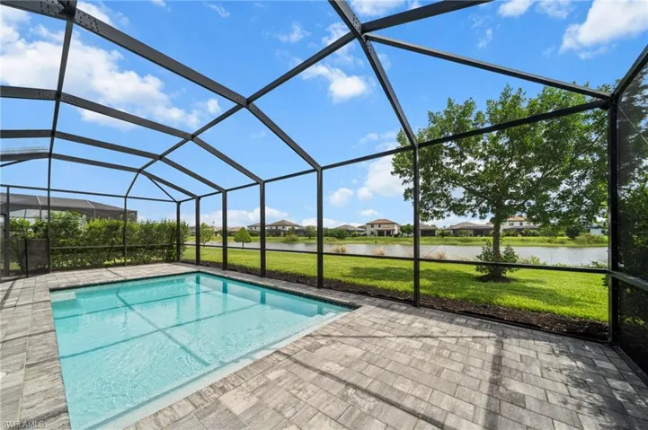Swimming pool with a water view, a lawn, and a patio