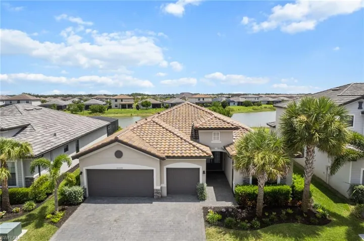 Mediterranean / spanish-style home featuring a garage, a residential view, stucco siding, decorative driveway, and a water view