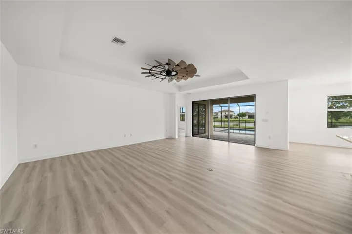 Unfurnished living room with a raised ceiling and light wood-type flooring