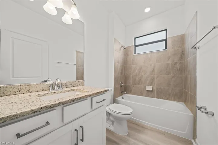 Full bath featuring wood finished floors, vanity, tub / shower combination, and a chandelier