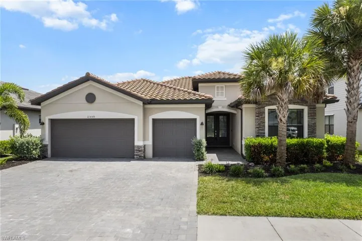 Mediterranean / spanish house with french doors, stone siding, a garage, stucco siding, and decorative driveway