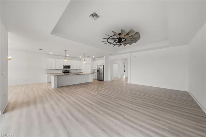 Unfurnished living room with a tray ceiling, recessed lighting, and light wood-style flooring