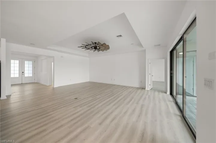 Unfurnished room with a tray ceiling and light wood-type flooring