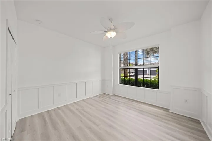 Spare room with a wainscoted wall, light wood-type flooring, a ceiling fan, and a decorative wall