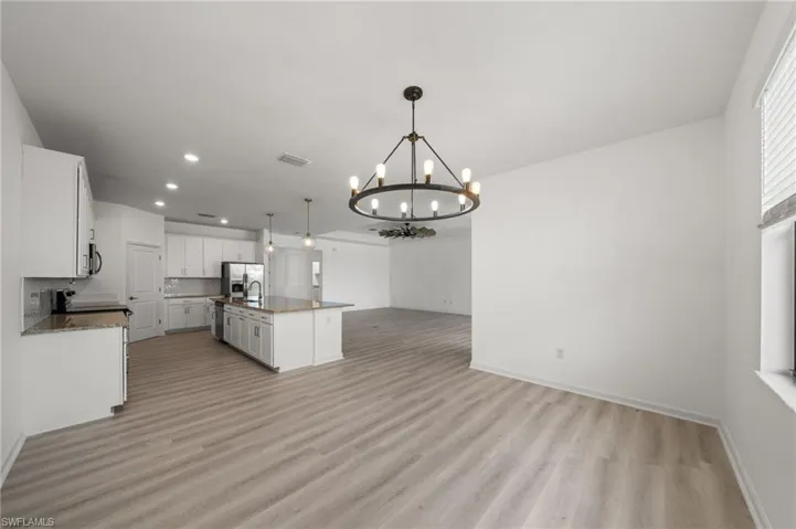 Kitchen with open floor plan, recessed lighting, light wood-style floors, a chandelier, and white cabinets