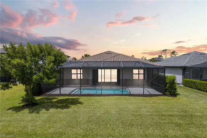 Rear view of house with a yard, a patio, stucco siding, and a lanai