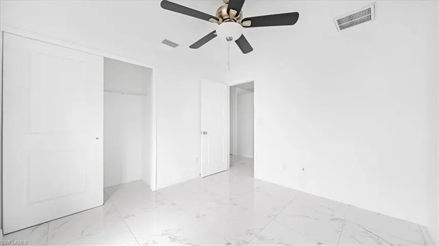 Unfurnished bedroom with light marble finish floors, a closet, and ceiling fan