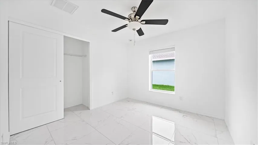 Unfurnished bedroom with light marble finish floors, ceiling fan, and a closet