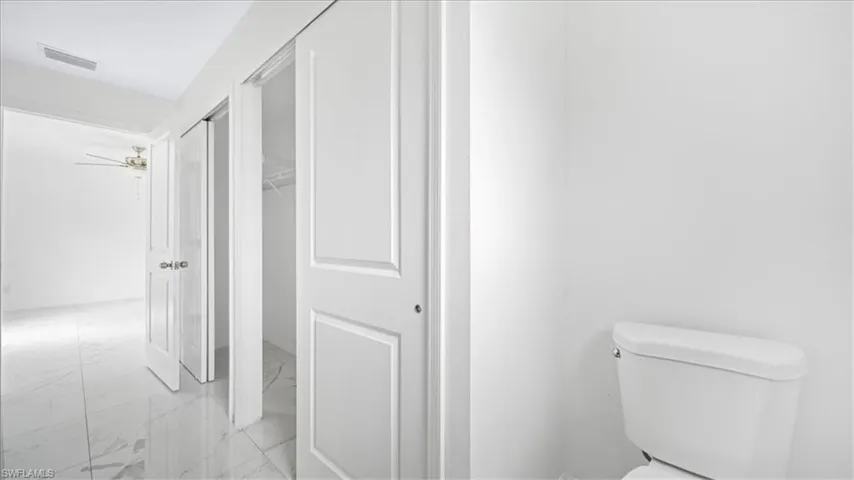 Bathroom featuring light marble finish floors and a walk in closet