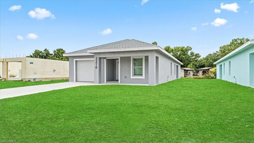 View of front of home with a front lawn, driveway, an attached garage, and stucco siding