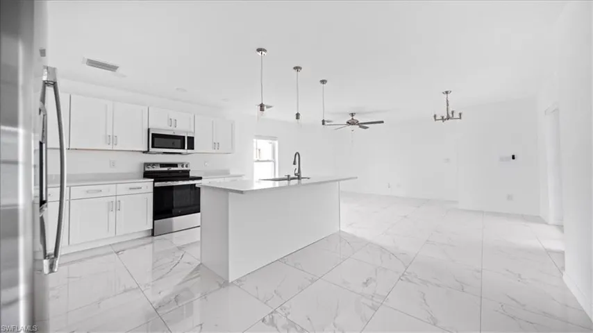 Kitchen with stainless steel appliances, ceiling fan, pendant lighting, and white cabinetry