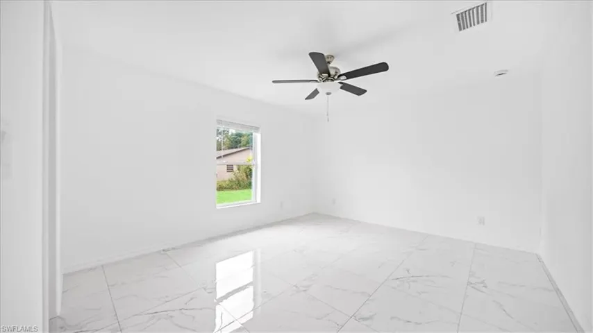 Empty room with light marble finish floors and ceiling fan