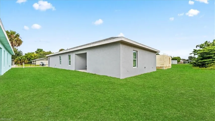Back of property featuring a yard and stucco siding