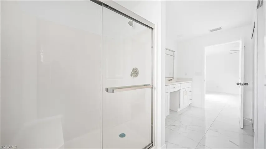 Bathroom with light marble finish floors, vanity, and a stall shower