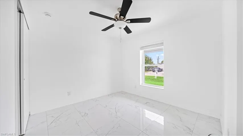 Spare room featuring light marble finish flooring and a ceiling fan