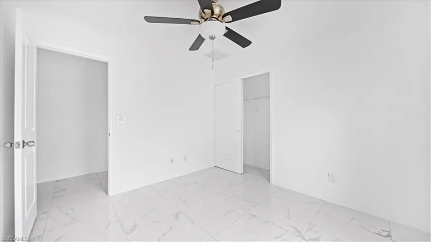 Unfurnished bedroom featuring light marble finish floors, ceiling fan, and a closet